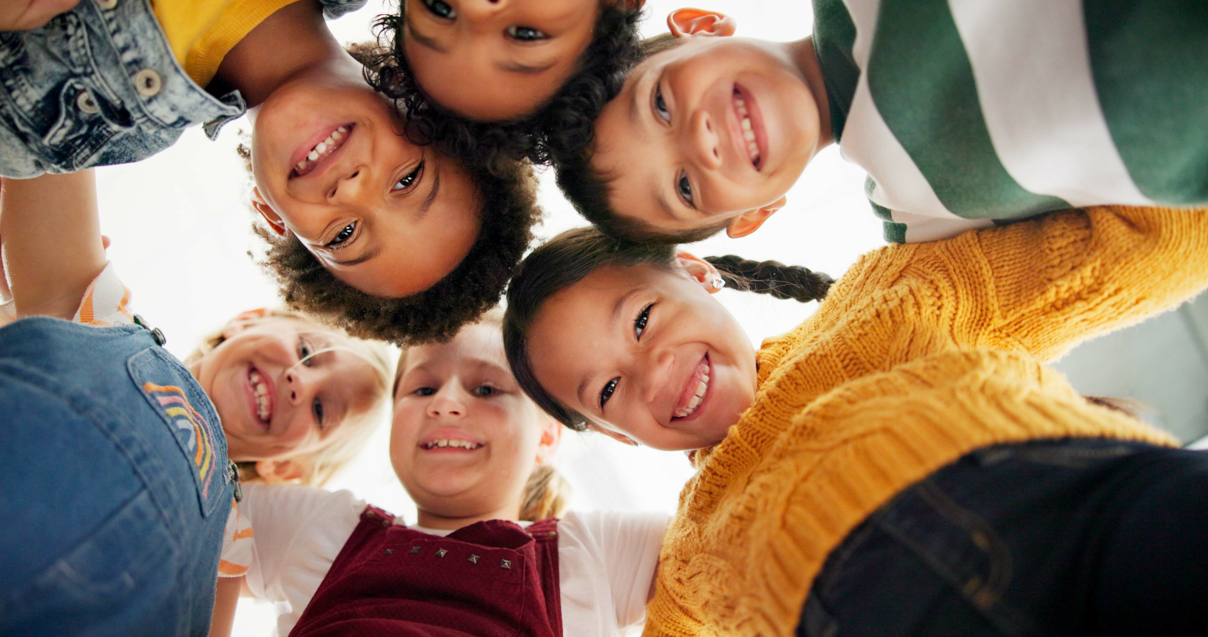 Niños sonriendo en círculo mirando a la cámara